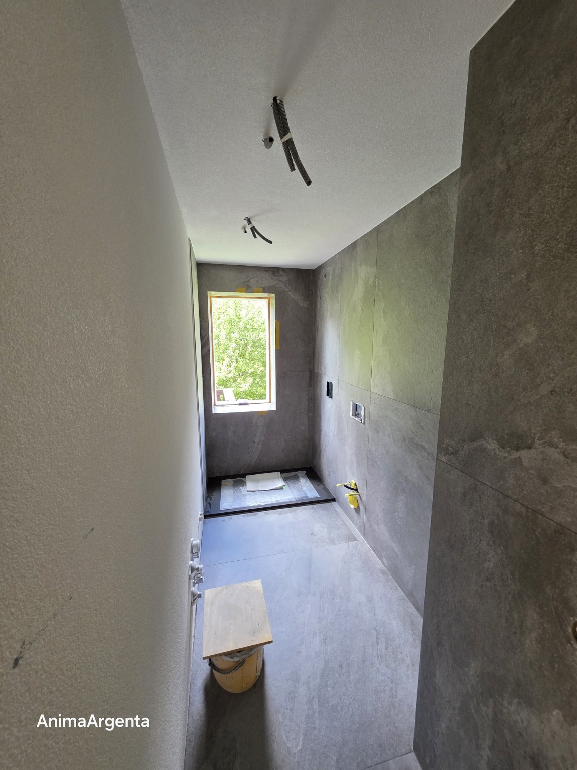 Vista del bagno con pavimento e rivestimento grigio durante la posa