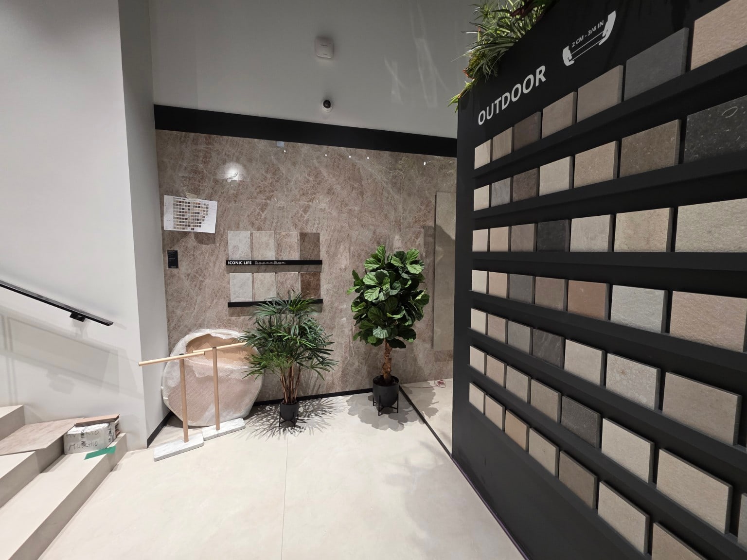 Zona espositiva con parete ceramica effetto pietra, pavimento chiaro e campioni di superfici