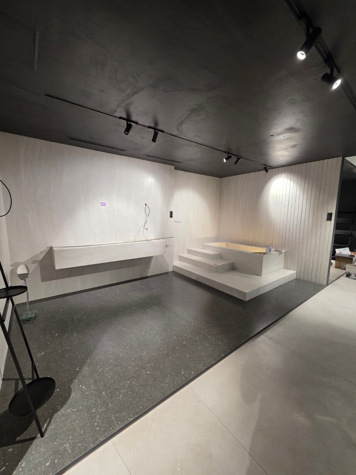 Ambiente bagno dello showroom con rivestimenti chiari, lavabo sospeso e vasca rivestita su pedana